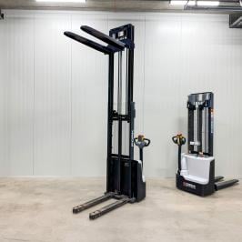 Elektriskais grēdotājs EG15-30 palešu pacelšanai. Skats no sāniem ar paceltām dakšām noliktavā